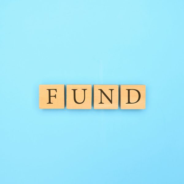 Fund text written on wooden block with abstract blue background